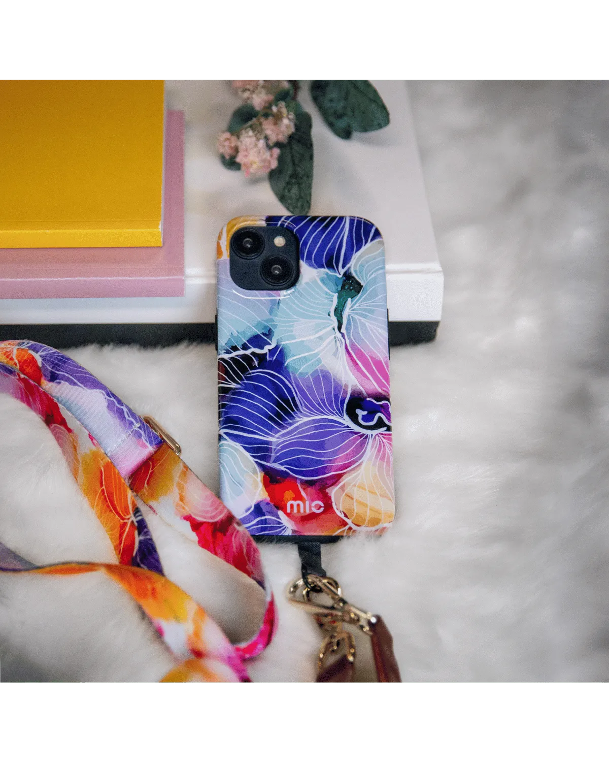 Flatlay van het Mio Flowers hoesje met bloemenprint en bijpassend koord op zachte ondergrond.